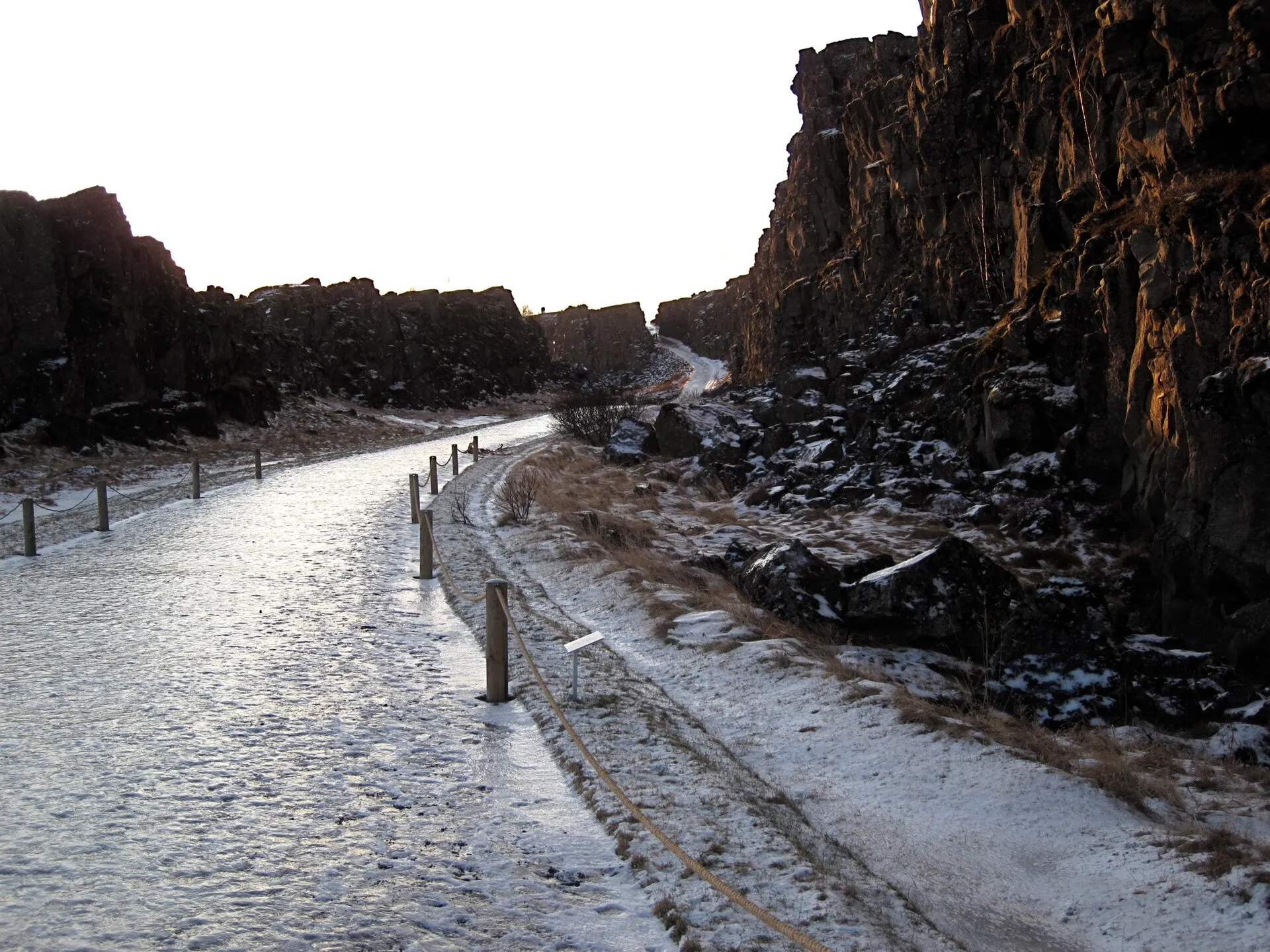 Ścieżka w wąwozie Almannagjá w Þingvellir zimą, między ścianami skalnymi płyty północnoamerykańskiej