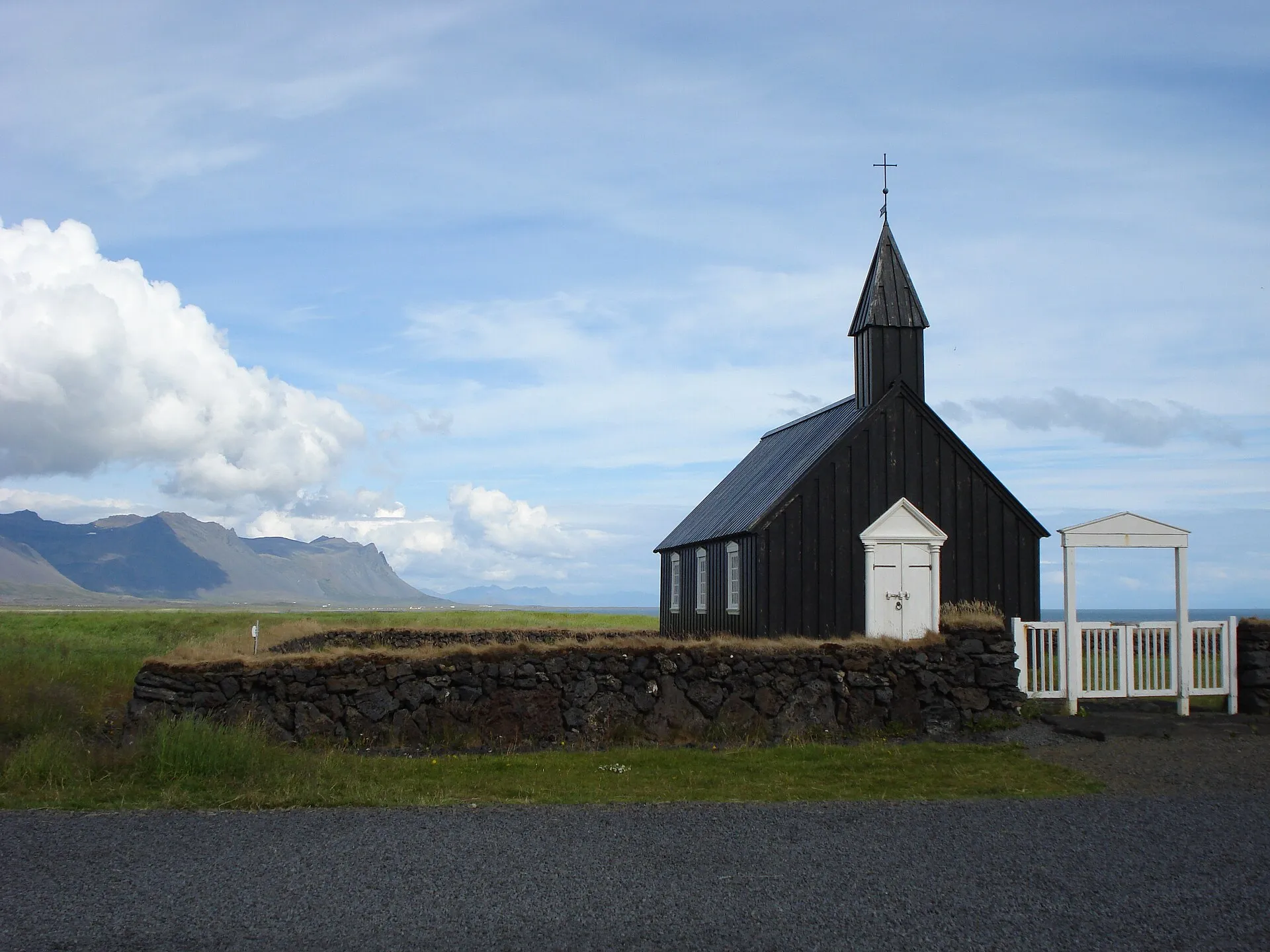 Czarny drewniany kościół w Búðir na półwyspie Snæfellsnes, w tle góry