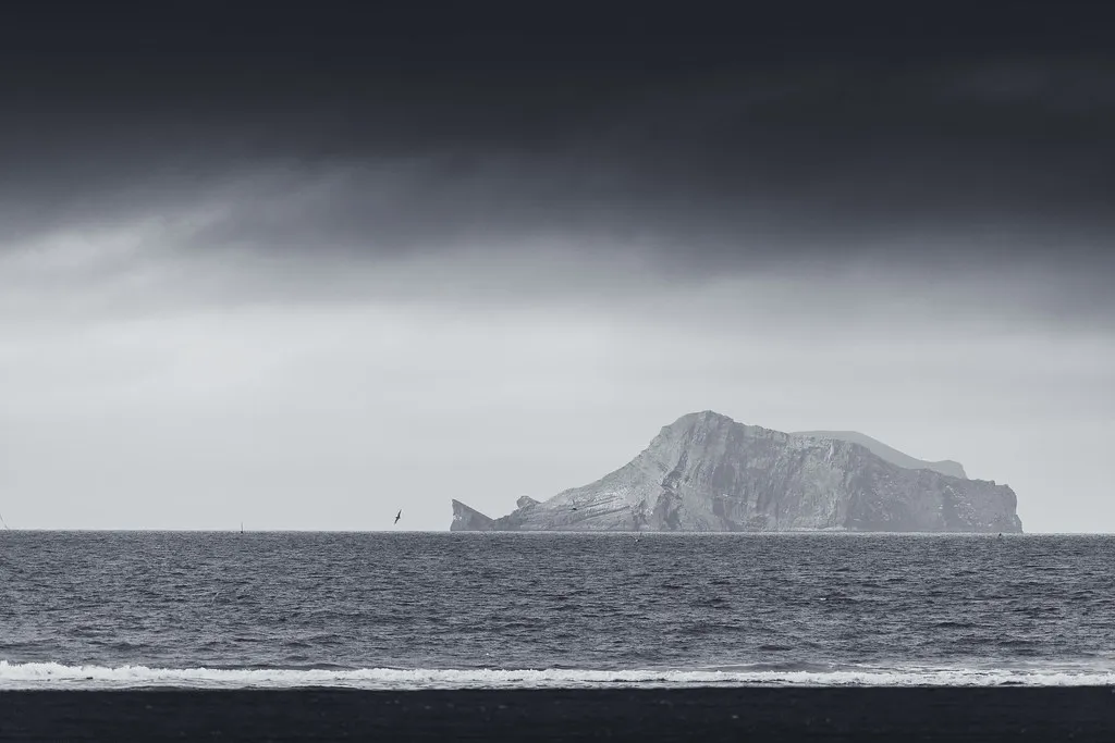 Wyspa z archipelagu Vestmannaeyjar widziana z czarnej plaży na stałym lądzie