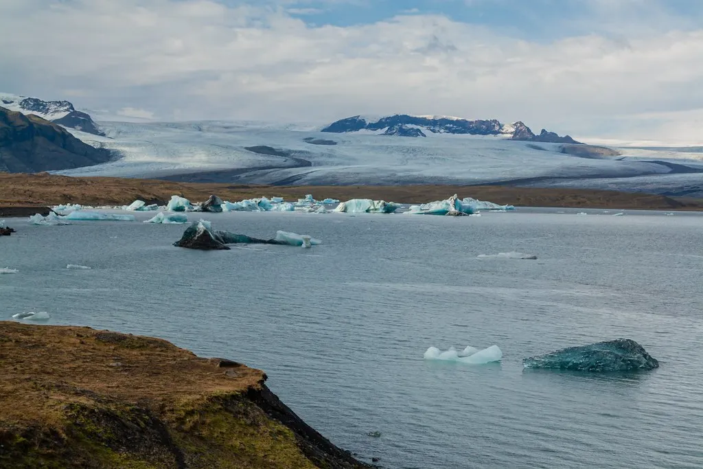 Góry lodowe na lagunie Jökulsárlón, w tle szeroki jęzor lodowca Breiðamerkurjökull i ośnieżone szczyty