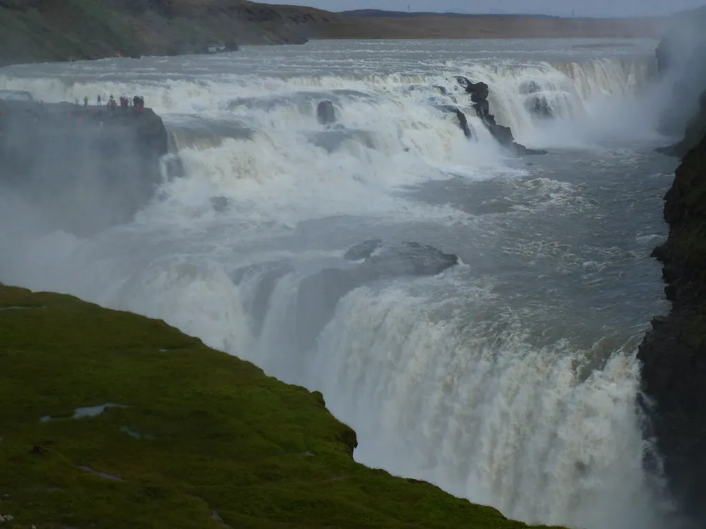 Gullfoss widziany z góry – obie kaskady i turyści na skalnym występie przy końcu dolnej ścieżki