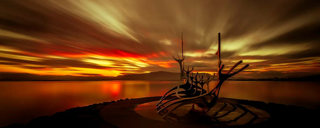 Rzeźba Sólfar (Sun Voyager) na nabrzeżu w Reykjavíku na tle kolorowego nieba po zachodzie słońca