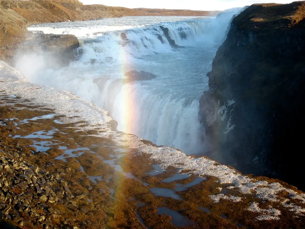 Tęcza w mgiełce nad dolną kaskadą Gullfoss, wczesną wiosną, z resztkami śniegu na brzegu kanionu