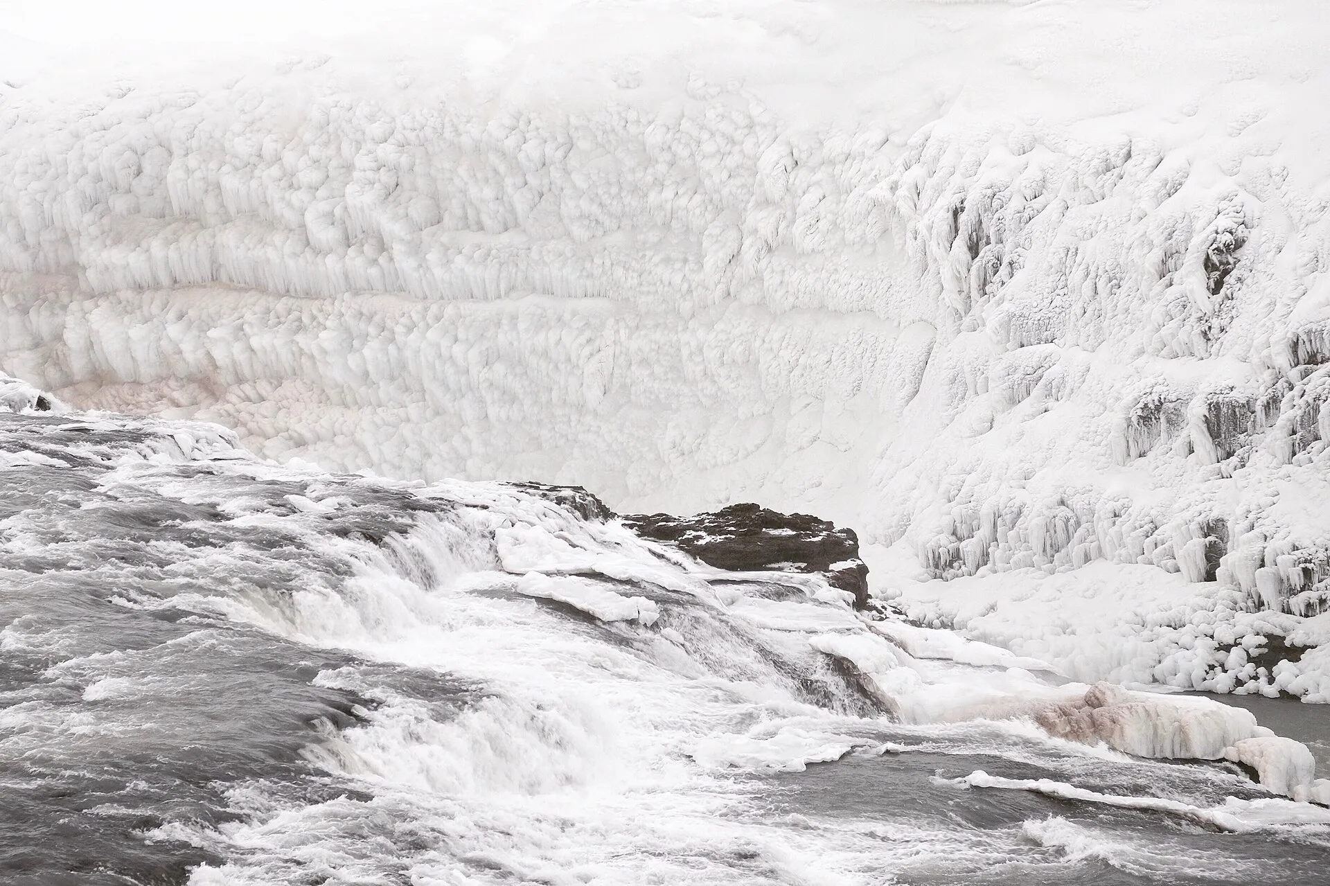 Zamarznięty Gullfoss zimą – rzeka spływająca kaskadą przed ścianą lodu i oszronionych skał